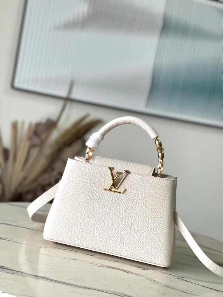 The M23944 white small size Capuchines BB handbag is adorned with Taurillon cowhide accents and shimmering metal pieces and features 3D strokes to ex