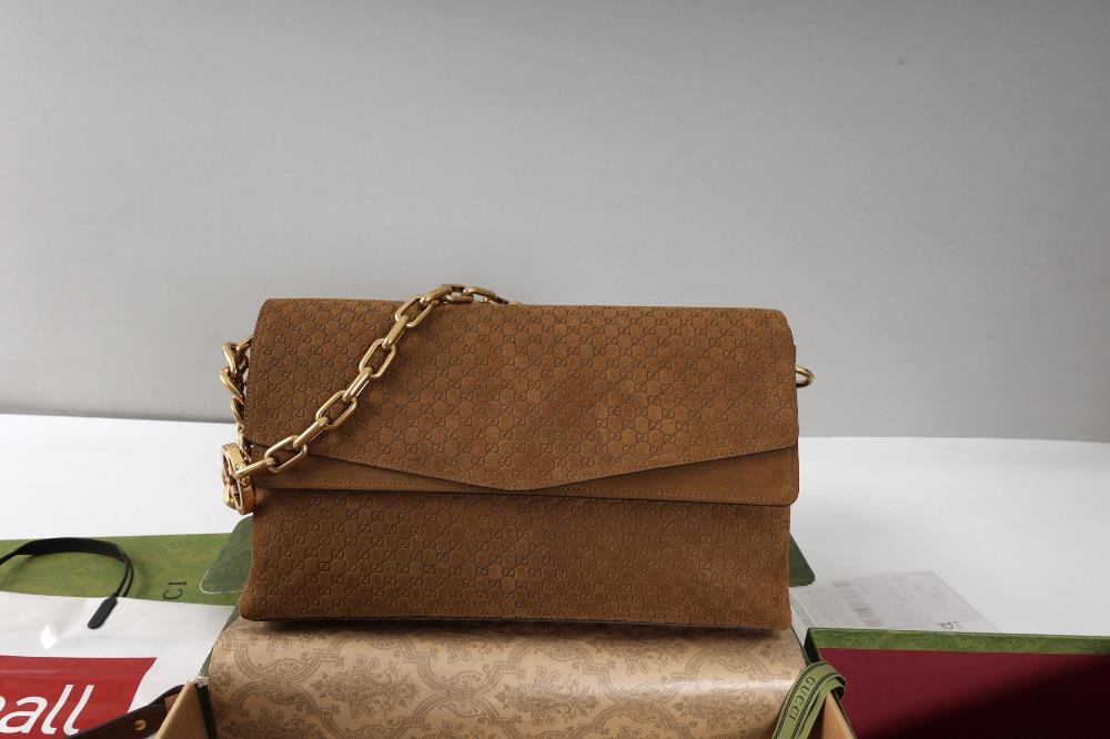 This handbag combines a modern silhouette with the brands iconic pattern This sleek cut handbag is paired with a gold toned chain adorned with circu